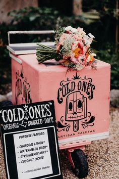 an old - fashioned icebox with flowers on top and a sign for cold ones