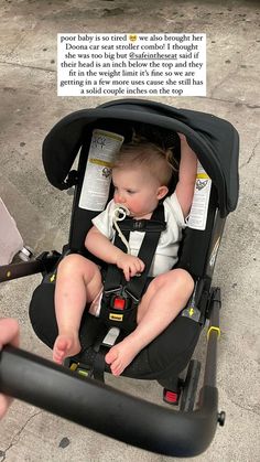 a baby sitting in a stroller being held by someone's hand and holding the handle