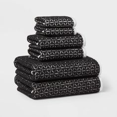 five black towels stacked on top of each other in front of a white background with triangles