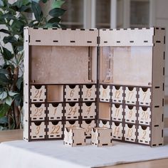 an open wooden box with numbers inside on a table next to a potted plant