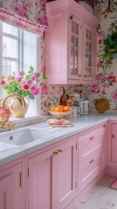 a kitchen with pink cabinets and floral wallpaper