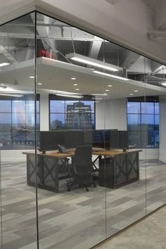 an empty office with glass walls and desks