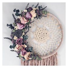 a white doily with flowers and greenery on it next to a wall hanging