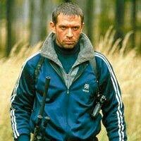 a man in blue jacket walking through tall grass