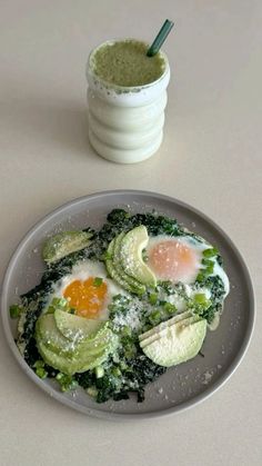 an egg and avocado dish on a plate next to a shaker filled with pesto