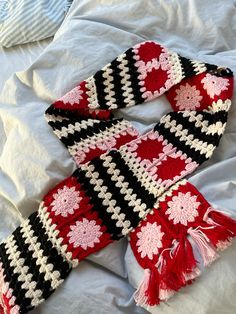 a scarf laying on top of a bed covered in white and black crochet