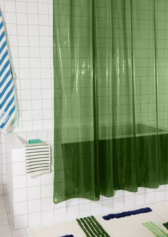 a bathroom with green shower curtains and blue rugs