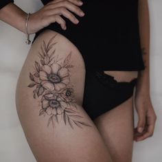 a close up of a person's thigh with flowers on the side and behind her