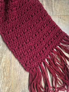 a crocheted red scarf laying on top of a wooden floor