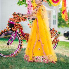 a woman in a yellow dress standing next to a bike with flowers on the front