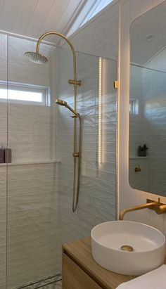 a bathroom with a sink, mirror and shower head in it's glass enclosure