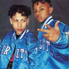 two young boys wearing blue jackets and pointing at the camera with their fingers in the air