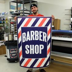 a man holding a sign that says barber shop