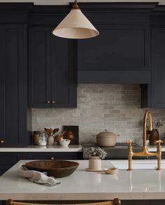 a kitchen with dark blue cabinets and white counter tops, gold faucet lights