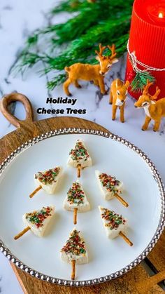 holiday cheese trees on a white plate next to a red candle and christmas tree decoration