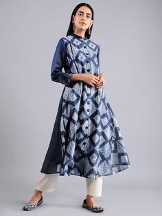 An Indigo diamond shaped all over shibori jacket dress with mirror work and flower shapped handmade buttons. This dress comes with a separate matching slip in mul. Features: Front open jacket dress with 3/4th sleeves Shell - pure cotton silk fabric Lining - separate matching slip in soft cotton Handmade in India Measurements: Size XS : Bust-34", Waist-33", Hip-Flared, Shoulder-14", Length-47", Sleeve length-18" Size S : Bust-36", Waist-35", Hip-Flared, Shoulder-14.5", Length-47", Sleeve length-1 Spring Handloom Chanderi Kurta, Traditional Festive Dresses With Set-in Sleeves, Eid Ikat Print Dress, Festive Tunic Kurta With Ikat Print, Festive Ikat Print Tunic Kurta, Indigo Cotton Silk Straight Kurta, Transitional Dresses With Printed Motifs, Traditional Bandhani Print Dress For Spring, Festive Chanderi Tunic Dresses