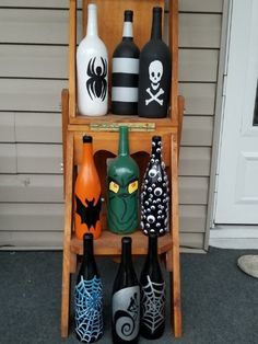 several bottles are sitting on a shelf with halloween decorations in them and one is painted black, the other orange