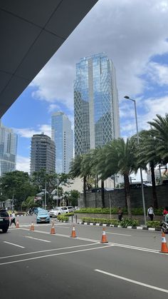 an empty parking lot with cars parked in front of some tall buildings and palm trees