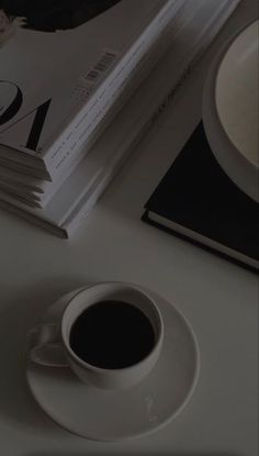 a cup of coffee sitting on top of a white table next to a stack of books