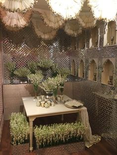 a table with some flowers on it in front of many umbrellas hanging from the ceiling