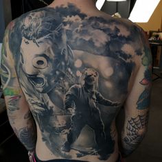 the back of a man's body with tattoos on it and an image of two people