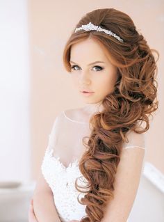 a woman with long brown hair wearing a tiara and braiding her hair in half - up style