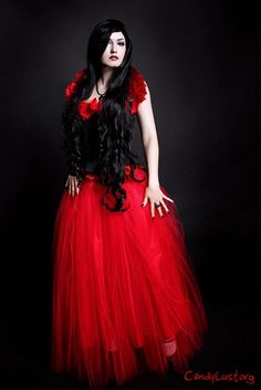 a woman in a red dress with long black hair and flowers on her head is posing for the camera