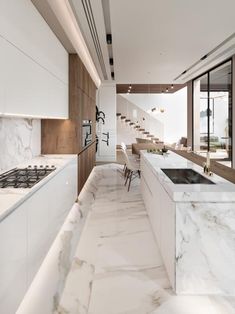 a kitchen with marble counter tops and white cabinets, along with stairs leading up to the second floor