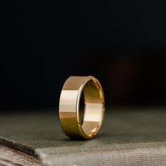 a gold wedding ring sitting on top of a book with the pages folded in front of it