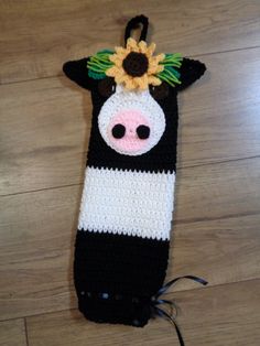 a black and white cow with a sunflower on its head