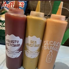 three ketchup bottles sitting on top of a table next to each other,