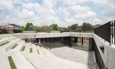 people are sitting on the concrete stairs in front of an open area with green arches