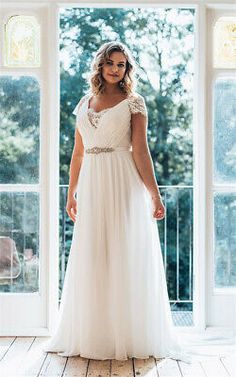 a woman wearing a white dress standing in front of a window