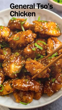 a white plate topped with chicken and chopsticks