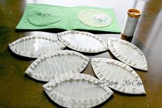 five paper plates sitting on top of a table next to a sewing needle and thread