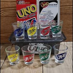 an assortment of glasses sitting on top of a tray next to a uno card game