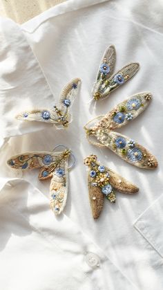 six brooches are laying on top of a white shirt with blue and yellow flowers