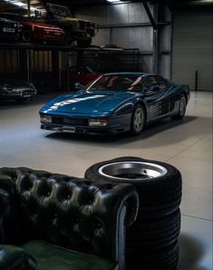 a blue sports car parked in a garage next to a black leather chair and ottoman