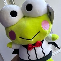 a green stuffed animal with big eyes and a bow tie on it's head