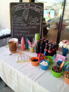 a table topped with lots of cups filled with desserts and drinks next to a chalkboard sign