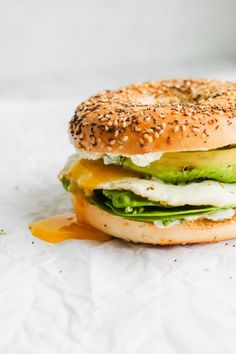 a bagel sandwich with cheese, lettuce and tomato