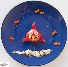 a blue plate topped with an orange fish next to small goldfish on top of it