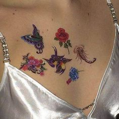 the back of a woman's neck with tattoos on it and flowers in different colors