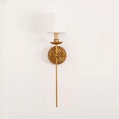 a wall mounted lamp with a white shade on it's side and a gold finish