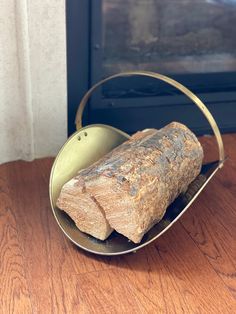 a piece of bread in a metal basket on a wooden table next to a window