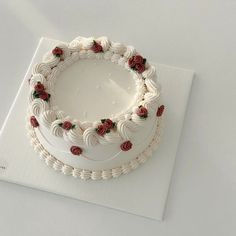 a white cake sitting on top of a table covered in frosting and red roses