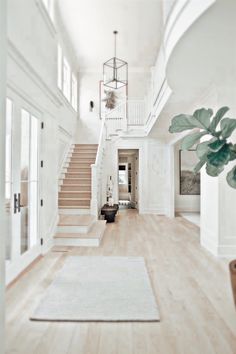 an open floor plan with white walls and wood floors, stairs leading to the second floor