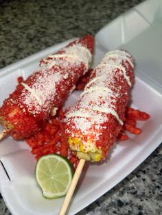 some food is sitting on a plate with two skewers and a lime wedge