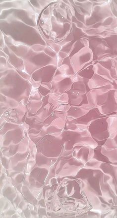 the water is pink and clear with some ripples on it's surface, as well as bubbles