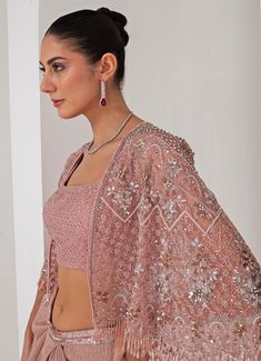 Elevate your style with the stunning Pastel Pink Draped Skirt with Embellished Cape, that effortlessly blends tradition with contemporary elegance. The pink cape features a sophisticated kimono sleeve , adorned with intricate florence embroidery using sequins, crystal tassels, cutdana, and bead highlights, adding a touch of opulence. Paired perfectly with a sequin jaal embellished blouse, it offers a dazzling appeal, making you the center of attention. Completed with a draped skirt, designed for a flattering silhouette, exudes grace and charm, ensuring comfort and sophistication in every movement. Ideal for, this ensemble is a timeless addition to your wardrobe, exuding both modernity and tradition in every detail. Composition : Cape - Organza ,Skirt - Platinoir Crepe Care: Dry Clean Only Designer Lehenga With Sequins And Cape Sleeves, Traditional Lehenga With Sequins And Cape Sleeves, Pink Lehenga With Dupatta And Cape Sleeves, Festive Pink Dress With Cape Sleeves, Pink Cape Sleeves Set With Dupatta, Traditional Pink Dress With Cape Sleeves, Pink Sets With Dupatta And Cape Sleeves, Festive Pink Lehenga With Cape Sleeves, Pink Lehenga With Sheer Dupatta And Cape Sleeves